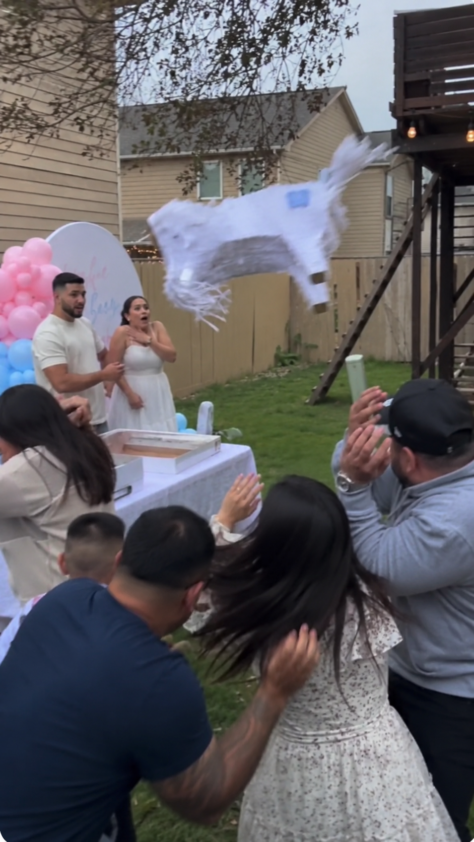 A backyard gender reveal moment with a pinata mid-air, family laughing, real Aussie reveal
